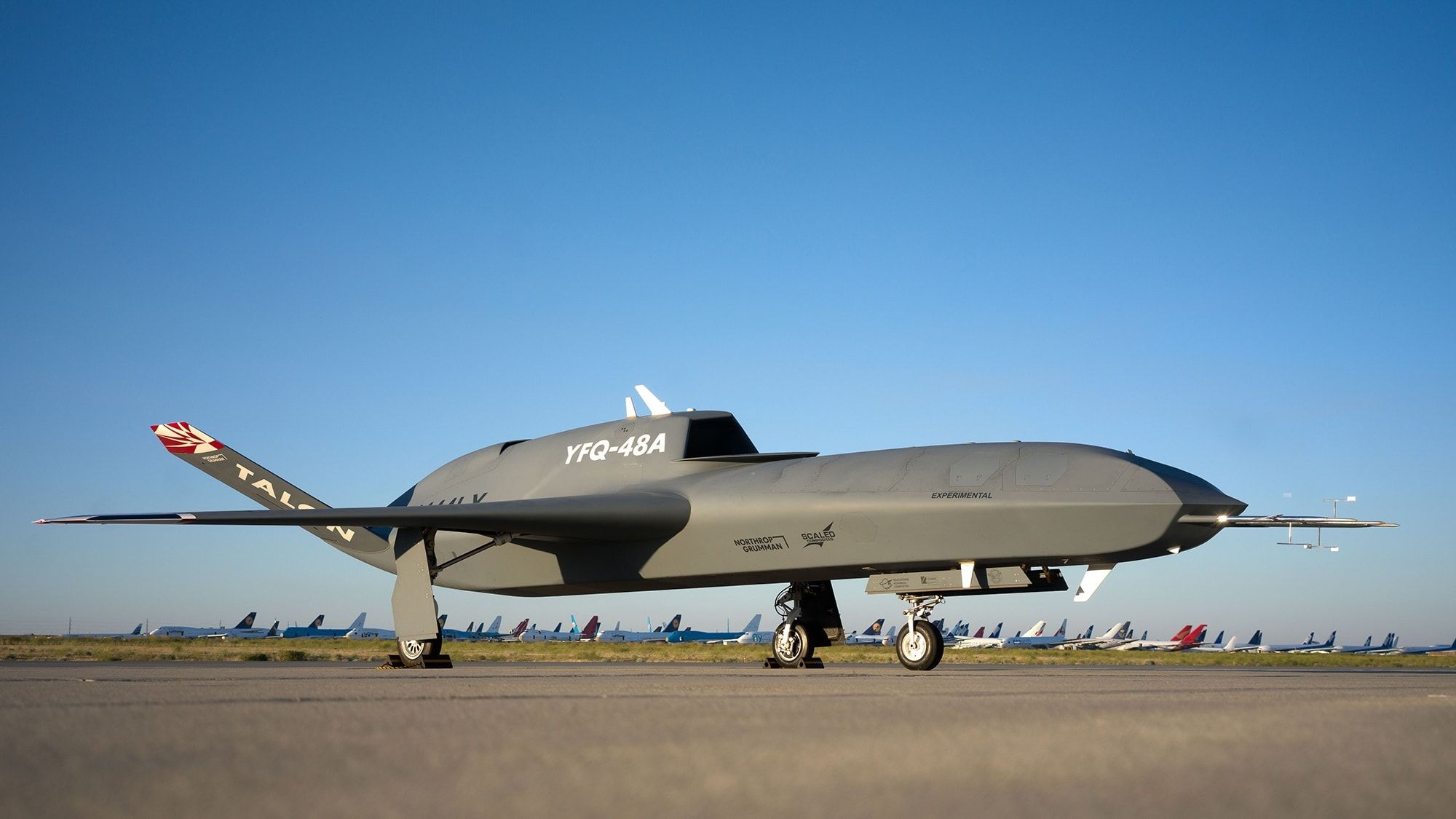 Northrop Grumman's YFQ-48A Talon Blue uncrewed aircraft parked on a desert ramp, seen from the side in low evening light.